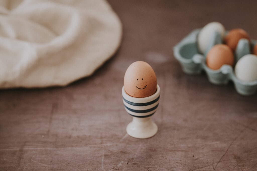 Photo by Aditya Romans on Upsplash Picture of striped egg cup containing an egg with a smile on it.